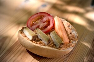 Halbes Brötchen bestrichen mit einer Granatapfelcreme und belegt mit Tofustreifen und Tomate