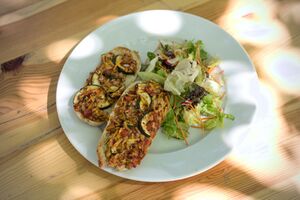 Aufbackbaguetts mit Ofengemüse auf einem Teller auf dem sich ebenso ein Beilagensalat befindet